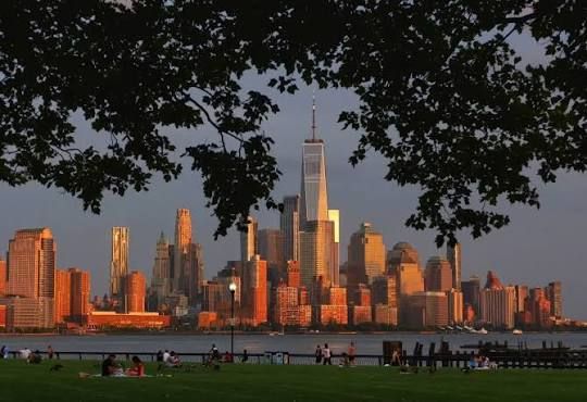 Pier C Park at sunset with Manhattan skyline in background