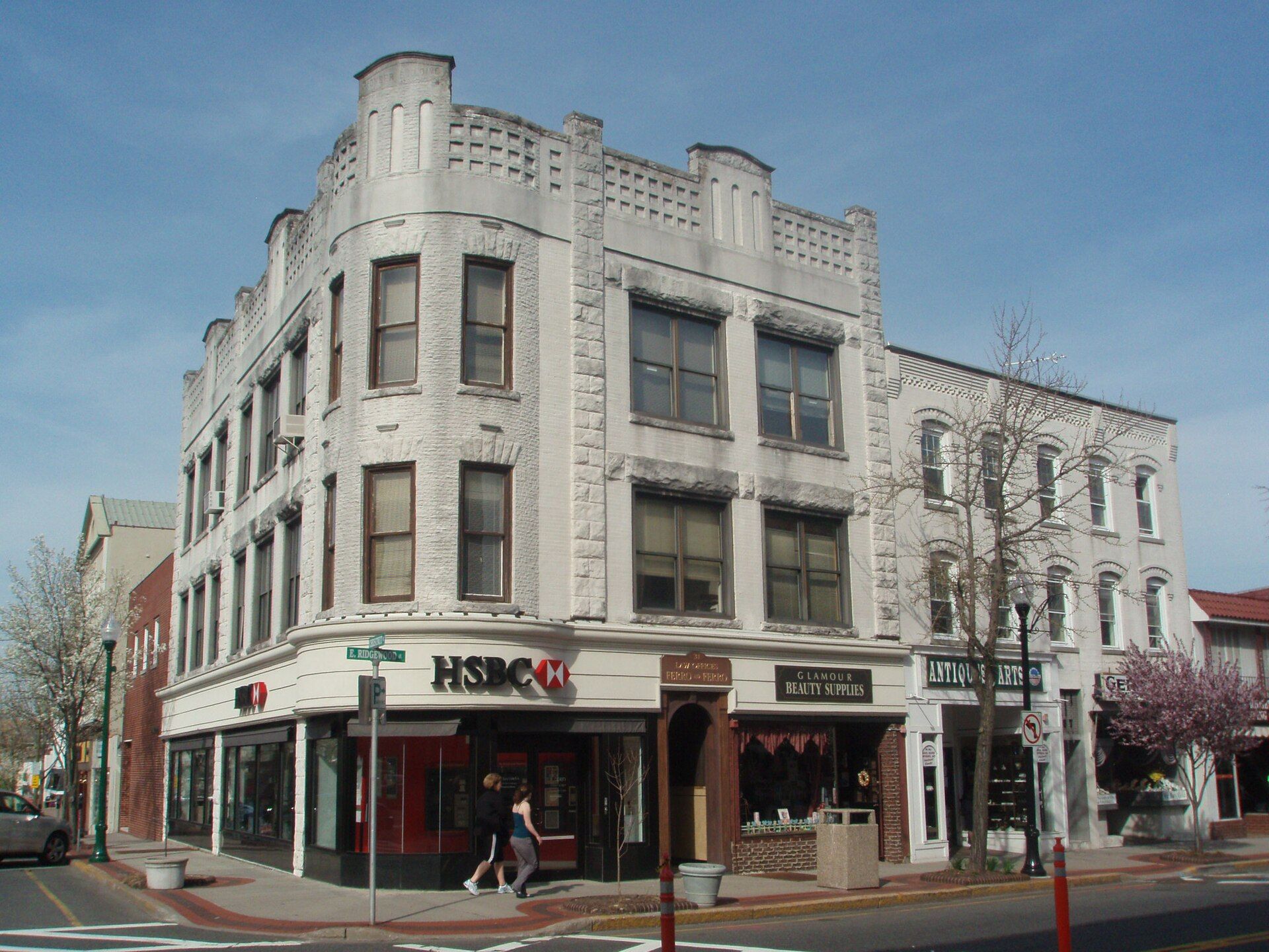 Downtown Ridgewood Avenue in early evening with lit storefronts and pedestrians